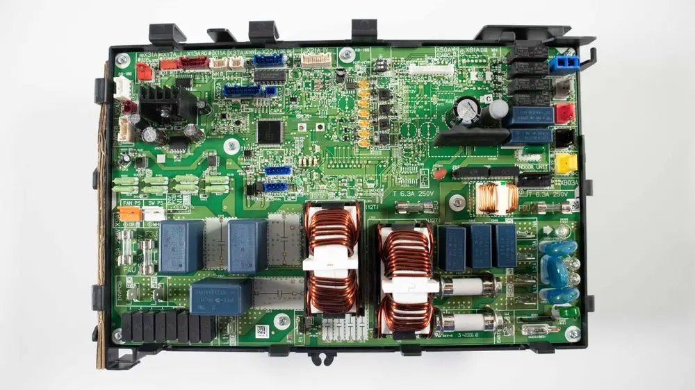 Grüne Platine mit Bauteilen wie Relais, Spulen und Widerständen, die typischerweise in Daikin-Geräten verwendet wird. Sichtbar sind mehrere Steckverbindungen und elektronische Komponenten.